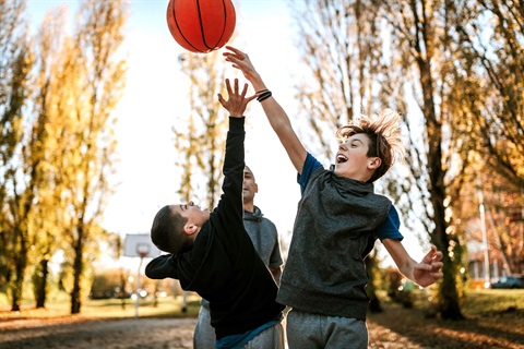 A group of three boys playing basketball