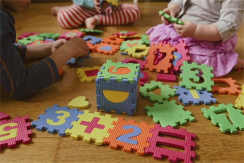 A pictur of several children playing with foam puzzel blocks.
